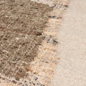 Detailaufnahme der Teppichkante des handgewebten Teppichs Briton 200x300 Beige mit meliertem Muster in Braun- und Beigetönen.