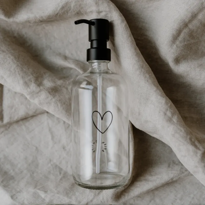 Seifenspender Herz 500ml mit schwarzem Pumpkopf auf Leinenstoff dekoriert – minimalistisches Design.