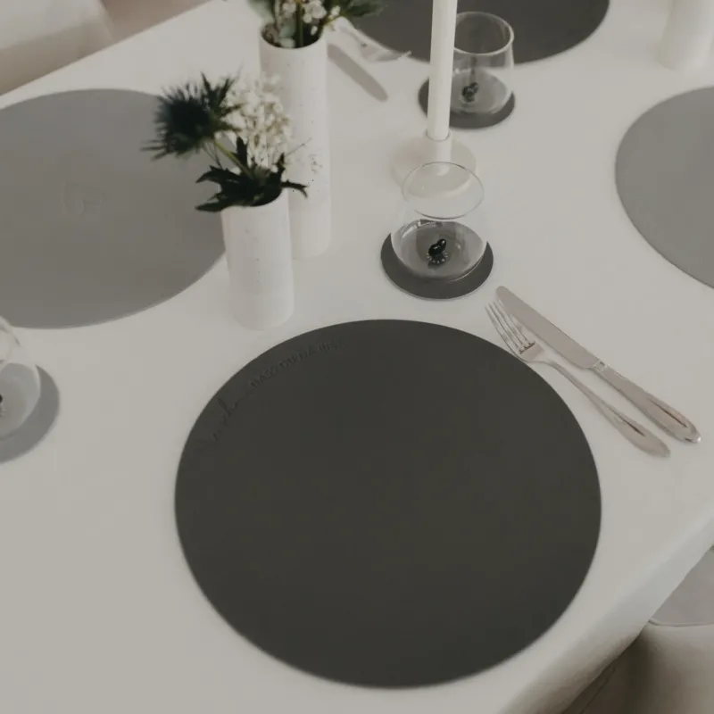 Gedeckter Tisch mit grauem, rundem Platzset und modernem, minimalistischem Tischarrangement.